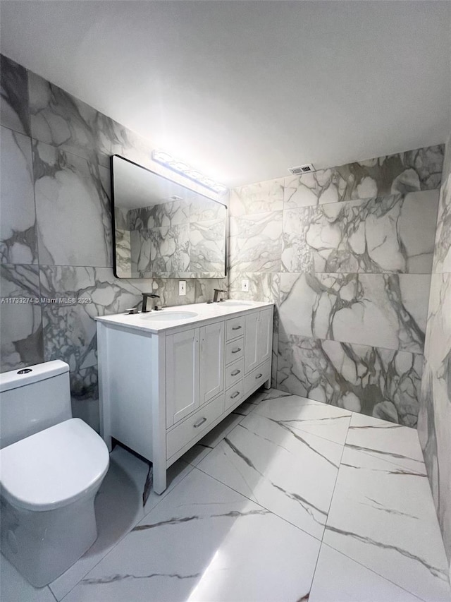 bathroom with double vanity, tile walls, visible vents, and a sink