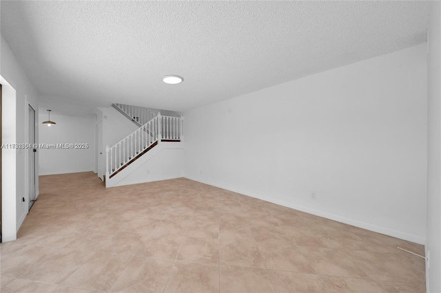 empty room with light tile patterned flooring and a textured ceiling