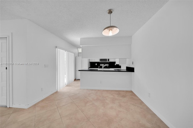 kitchen with light tile patterned flooring, sink, a textured ceiling, and kitchen peninsula