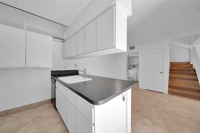 kitchen with light tile patterned flooring, sink, white cabinetry, a textured ceiling, and washing machine and dryer