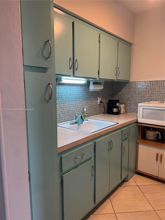 kitchen featuring light tile patterned flooring, sink, green cabinets, and decorative backsplash