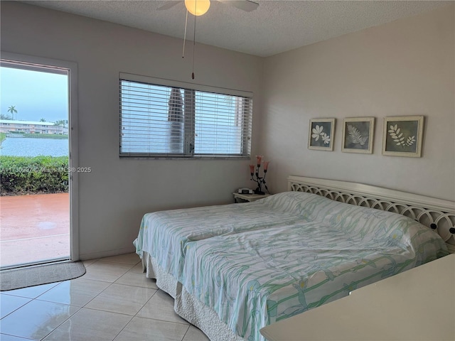 bedroom with a water view, ceiling fan, access to exterior, and a textured ceiling