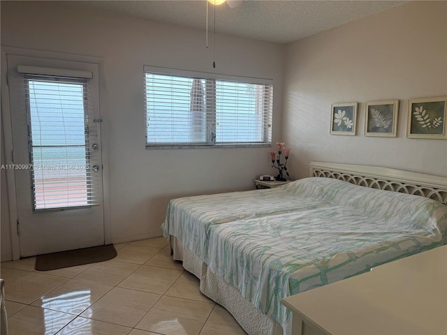 bedroom with ceiling fan, light tile patterned floors, and a textured ceiling