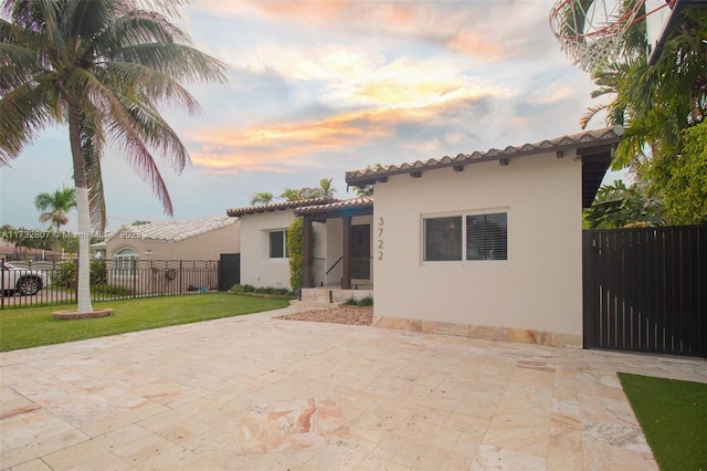 back of house featuring a lawn, a patio area, fence, and stucco siding