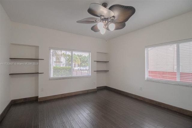 empty room with dark wood-style floors, a ceiling fan, and baseboards