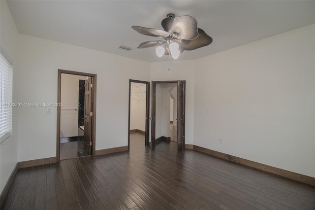 unfurnished bedroom with a ceiling fan, dark wood-style flooring, visible vents, and baseboards