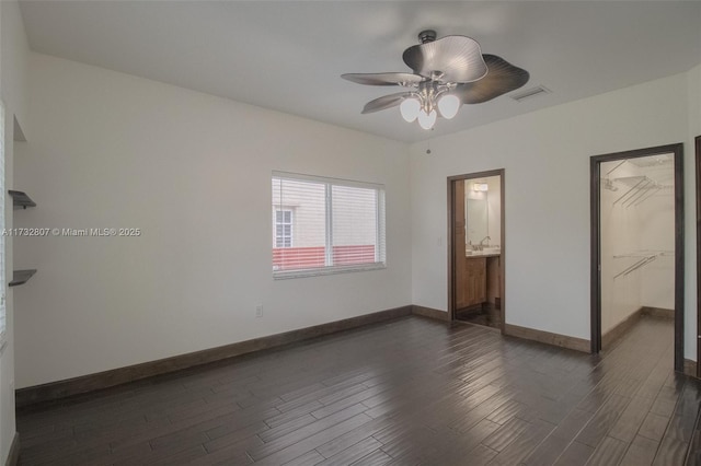 unfurnished bedroom with baseboards, visible vents, dark wood finished floors, ensuite bath, and ceiling fan