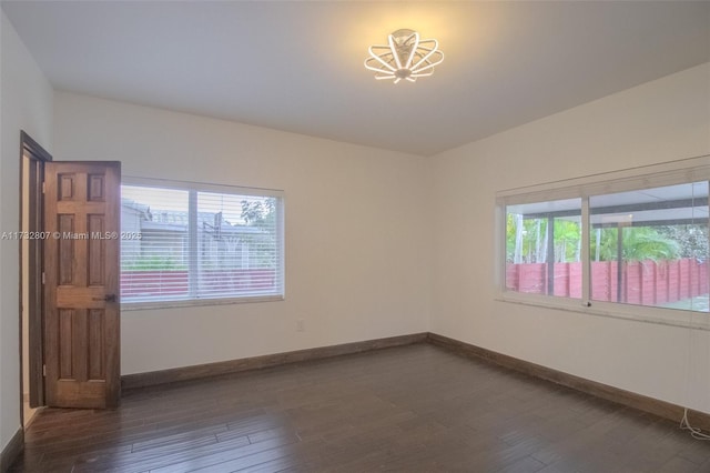 empty room featuring baseboards and dark wood-style flooring