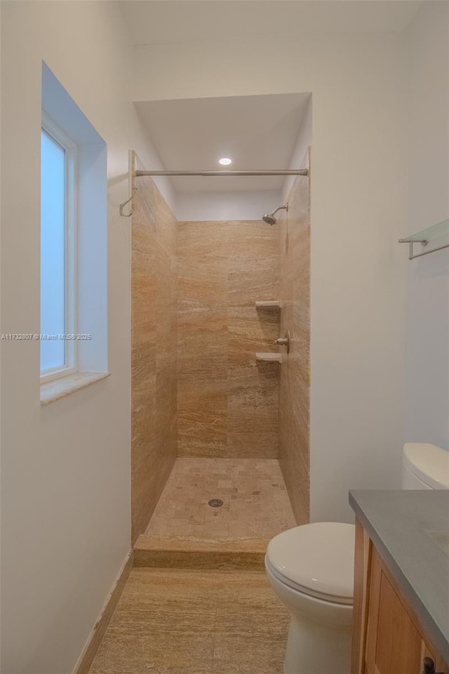 bathroom featuring baseboards, tiled shower, toilet, tile patterned floors, and vanity