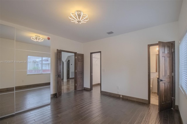 unfurnished room featuring dark wood-style floors, visible vents, and baseboards