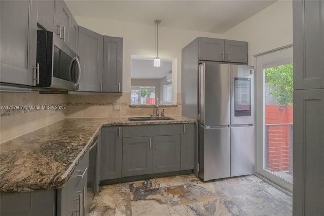 kitchen with stainless steel appliances, hanging light fixtures, backsplash, gray cabinetry, and a sink