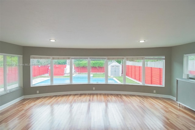 unfurnished room featuring light wood-type flooring, a wealth of natural light, and baseboards