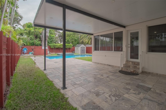 view of patio with entry steps, a shed, an outbuilding, and a fenced backyard