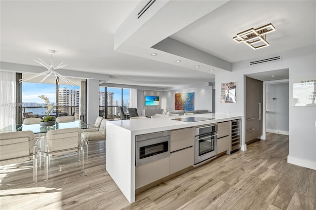 kitchen featuring light hardwood / wood-style flooring, white cabinetry, stainless steel appliances, a notable chandelier, and beverage cooler