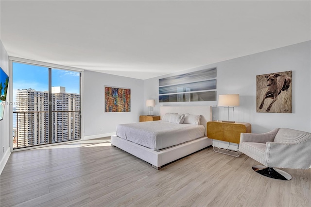 bedroom with light hardwood / wood-style floors and expansive windows