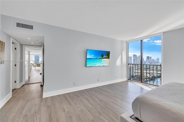 bedroom with expansive windows and light hardwood / wood-style floors