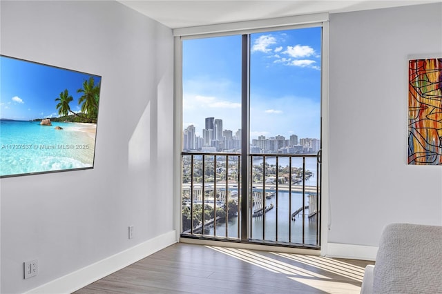 spare room with hardwood / wood-style floors, a wall of windows, and a water view