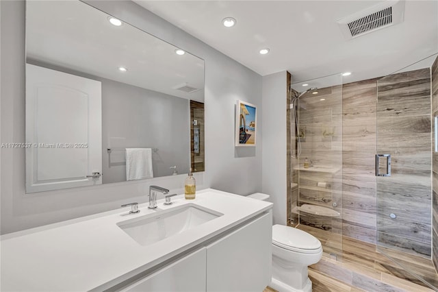 bathroom featuring vanity, toilet, and an enclosed shower