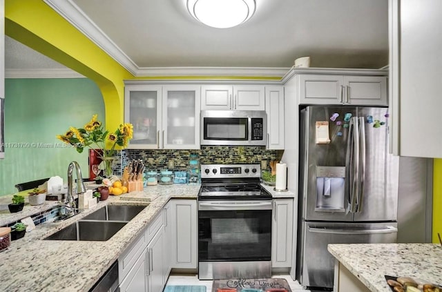 kitchen featuring sink, crown molding, backsplash, stainless steel appliances, and light stone countertops