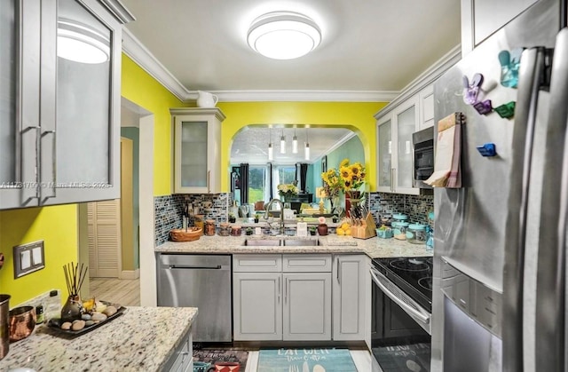 kitchen featuring light stone counters, appliances with stainless steel finishes, crown molding, and sink