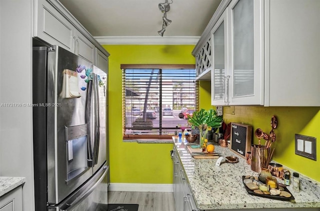 kitchen featuring stainless steel refrigerator with ice dispenser, gray cabinetry, light stone counters, light hardwood / wood-style flooring, and ornamental molding