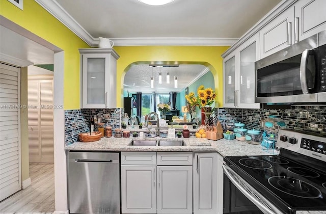 kitchen with light stone countertops, crown molding, appliances with stainless steel finishes, and sink