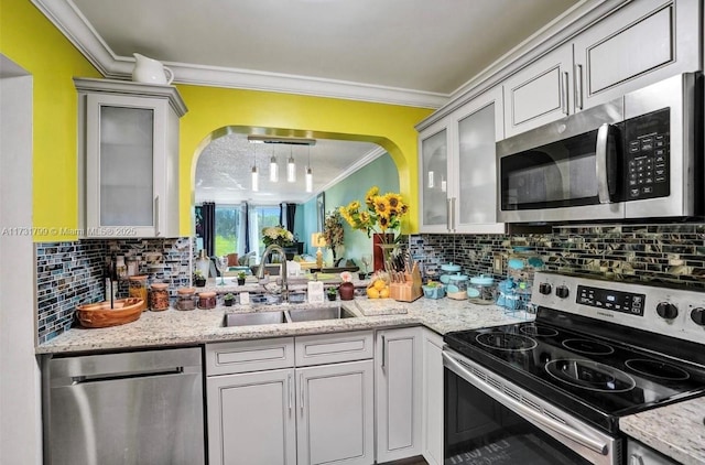 kitchen with light stone counters, ornamental molding, stainless steel appliances, and sink