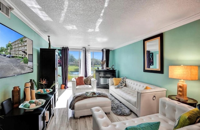 living room featuring light hardwood / wood-style flooring, ornamental molding, a textured ceiling, and a wall of windows