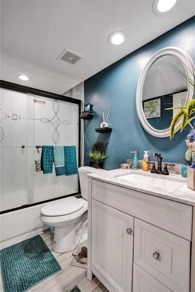 full bathroom featuring vanity, hardwood / wood-style flooring, toilet, and combined bath / shower with glass door