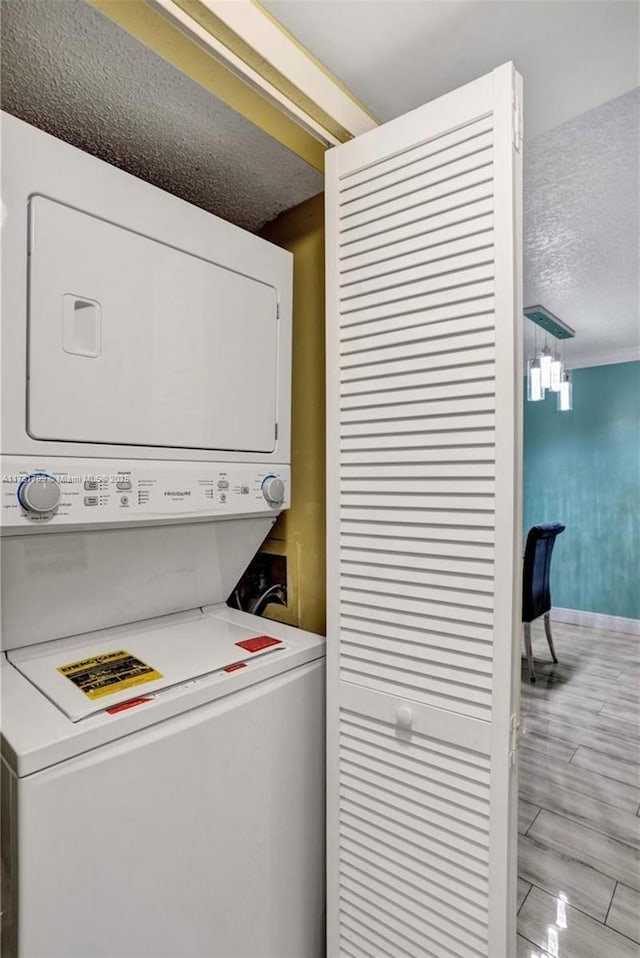 washroom featuring light hardwood / wood-style floors, a textured ceiling, and stacked washer / dryer