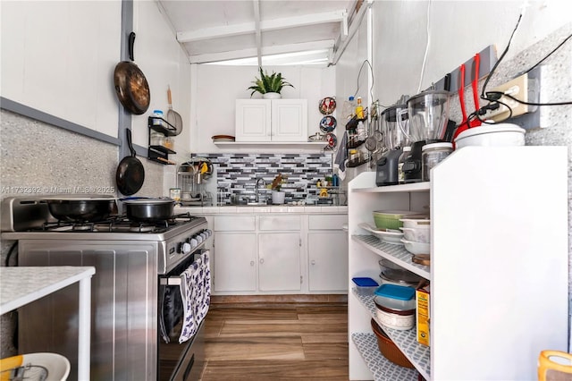 kitchen featuring wood finished floors, white cabinets, decorative backsplash, gas range, and tile counters