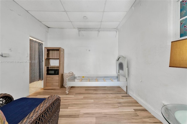 bathroom with wood finished floors, a paneled ceiling, and baseboards