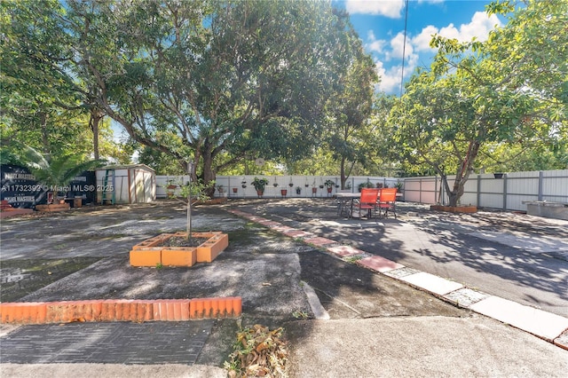 view of parking featuring a storage unit and fence