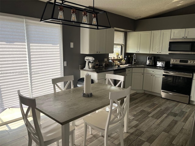 kitchen with sink, white cabinetry, a textured ceiling, appliances with stainless steel finishes, and dark hardwood / wood-style flooring