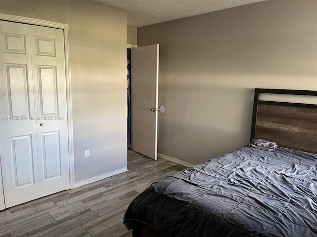 bedroom featuring hardwood / wood-style flooring, a closet, and a textured ceiling