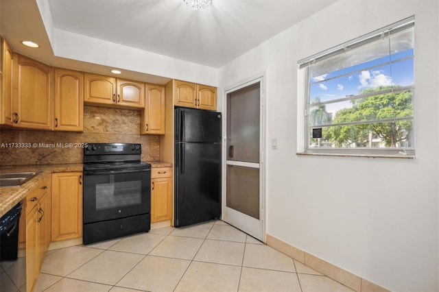 kitchen featuring backsplash, light tile patterned floors, black appliances, and stone counters