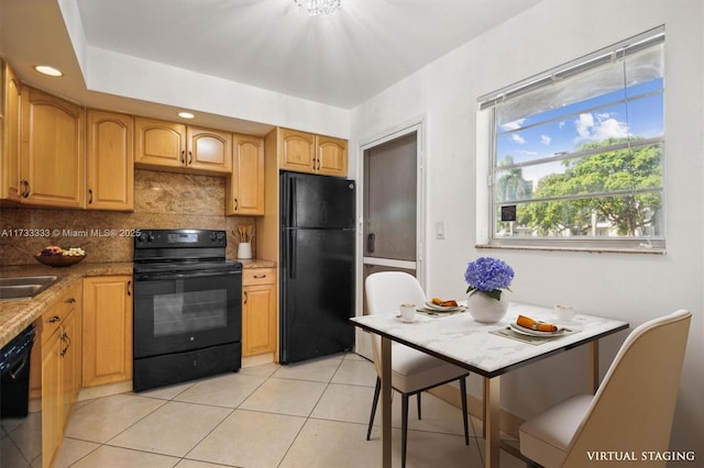 kitchen featuring tasteful backsplash, light tile patterned floors, black appliances, and sink