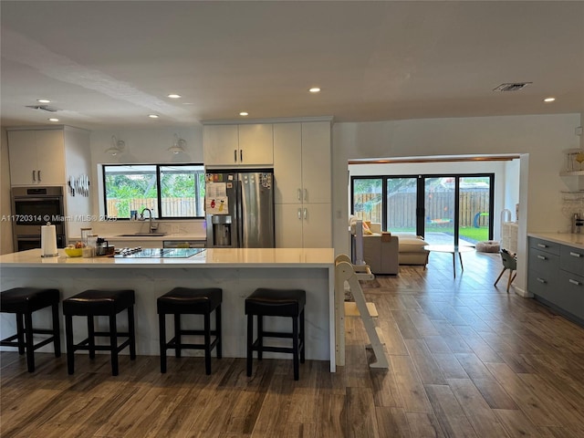 kitchen with gray cabinets, white cabinetry, sink, a breakfast bar area, and stainless steel appliances