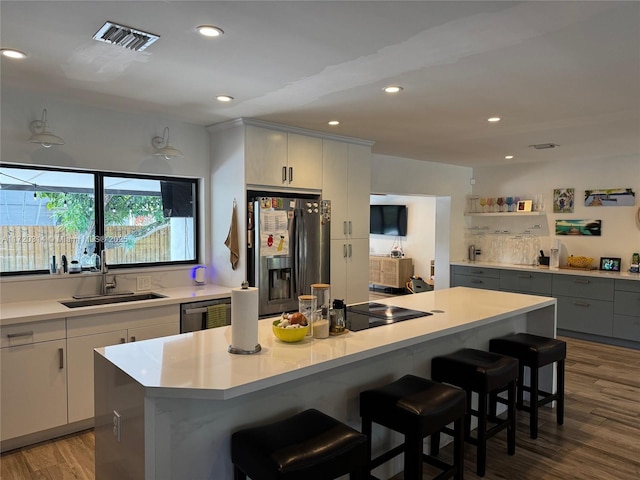 kitchen with a kitchen island, hardwood / wood-style floors, sink, a breakfast bar area, and stainless steel appliances