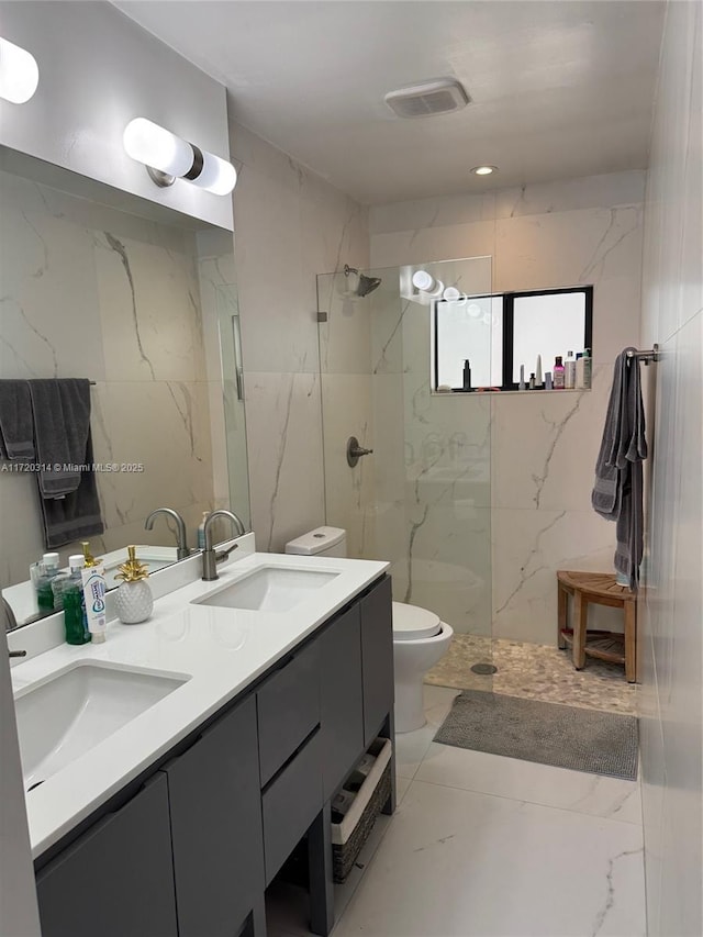 bathroom with vanity, tile walls, toilet, and tiled shower