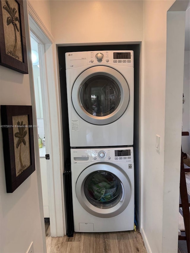 clothes washing area featuring light hardwood / wood-style flooring and stacked washer and clothes dryer