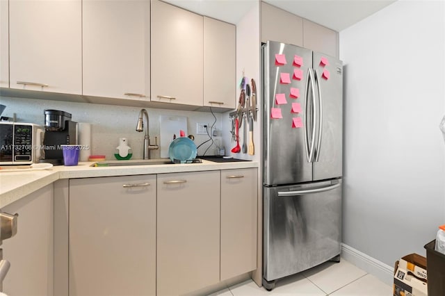 kitchen with light tile patterned flooring, sink, backsplash, and stainless steel refrigerator