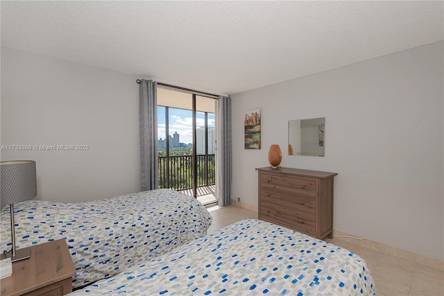 bedroom with access to exterior, light tile patterned floors, a wall of windows, and a textured ceiling