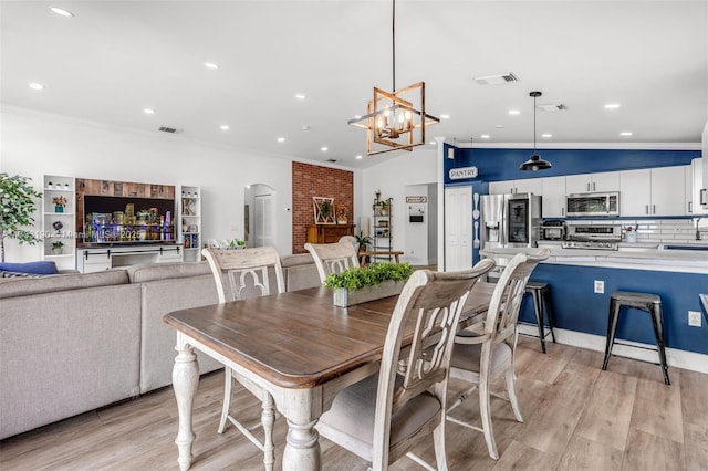 dining area featuring ornamental molding, arched walkways, visible vents, and light wood finished floors