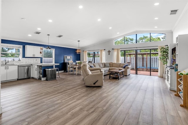 living area featuring light wood-style floors, lofted ceiling, visible vents, and crown molding