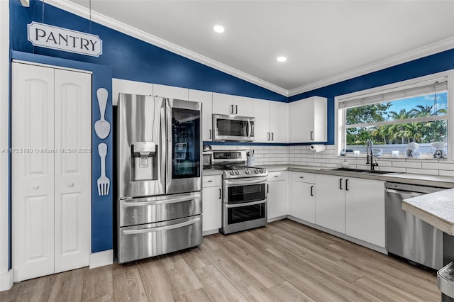 kitchen featuring stainless steel appliances, crown molding, a sink, and white cabinetry