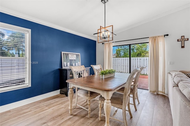 dining space featuring a chandelier, baseboards, crown molding, and light wood finished floors