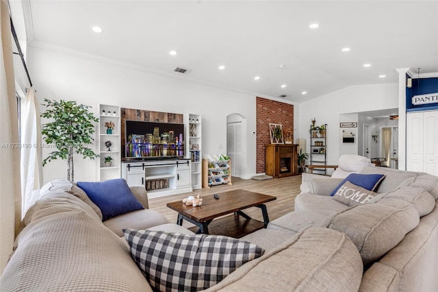 living room with visible vents, arched walkways, vaulted ceiling, light wood-type flooring, and a fireplace