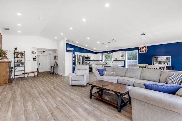 living area featuring baseboards, visible vents, vaulted ceiling, crown molding, and light wood-style floors