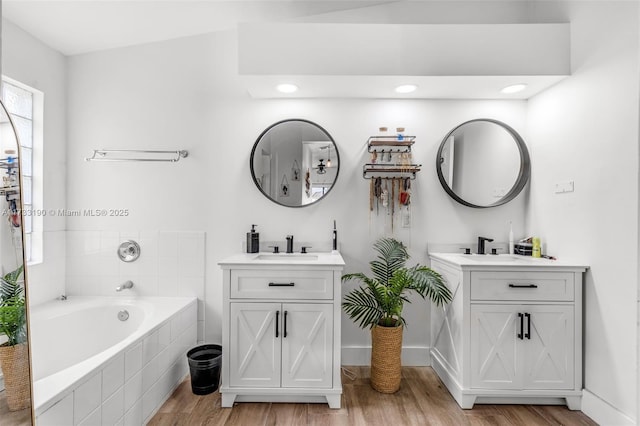 full bath with a garden tub, a sink, two vanities, and wood finished floors